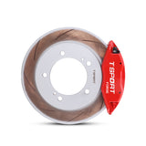 Close-up of a red TTSPORT Suzuki Jimny 4-piston forged brake caliper for the front wheel and a slotted rotor.